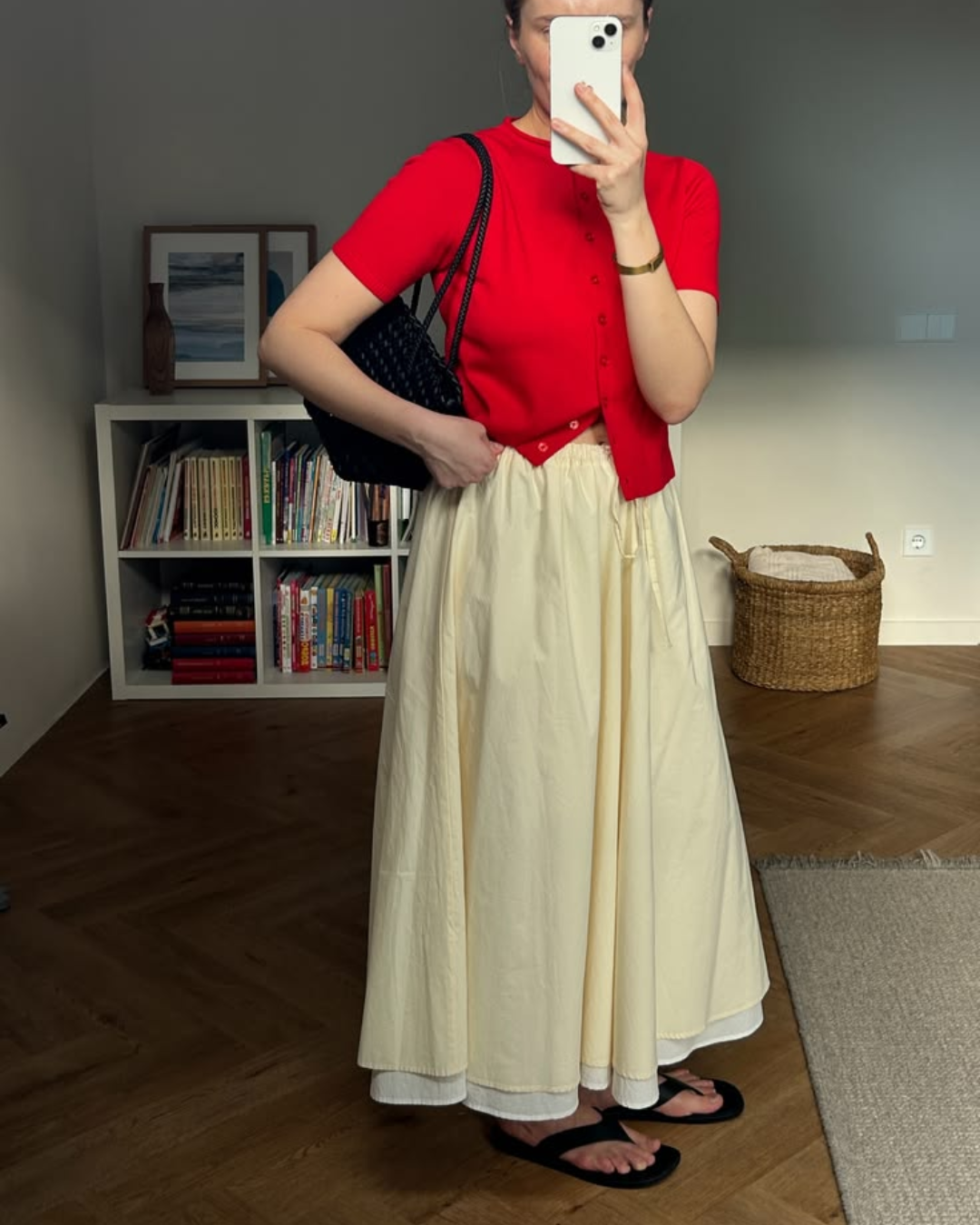 Bright tomato red short-sleeve knit cardigan layered with an off-white cotton maxi skirt and casual black flip-flops for a fresh summer look