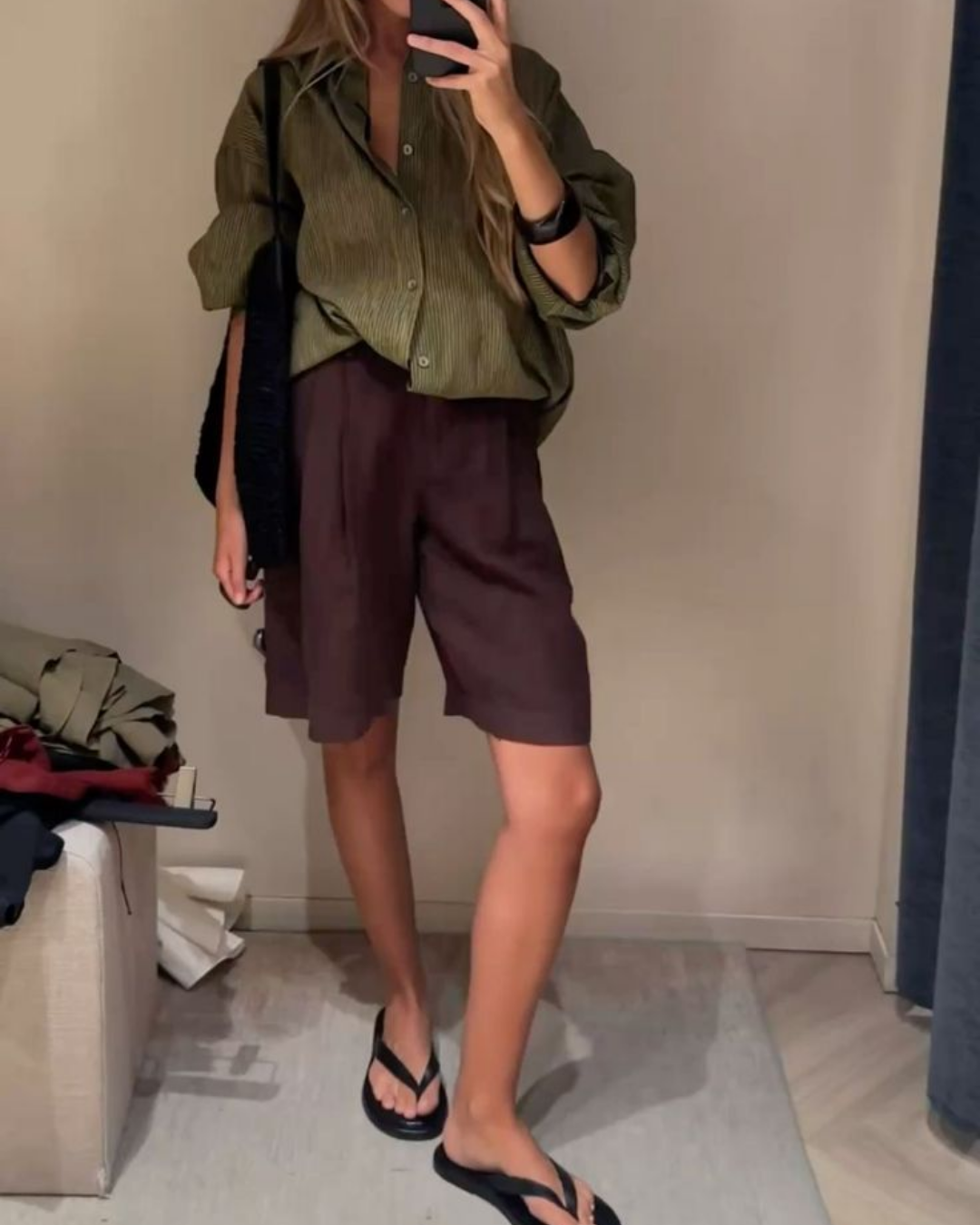 Relaxed summer styling with a loose-fit olive green striped shirt, deep brown linen bermuda shorts, and flat black leather sandals